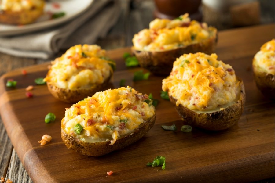 Twice baked potatoes with ham and cheese on a board.