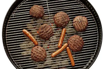 Meat and sausages cooking on a charcoal barbecue.