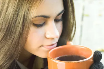 A woman with a cup of black coffee.