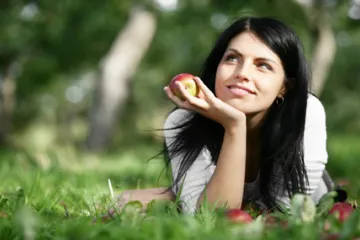 A young woman with an apple in the hand.