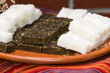 White and dark Guatemalan coconut sweets arranged on a terracotta plate.