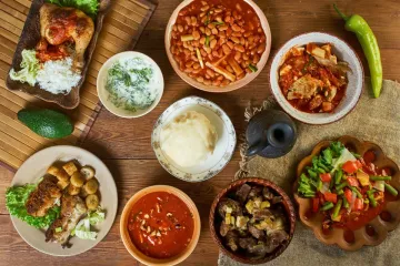 Assorted Congolese dishes including fufu, beans, rice, grilled meat, fish, and stews arranged on a wooden table.