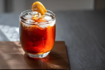 A glass of Vermouth with ice, decorated with a slice of orange.
