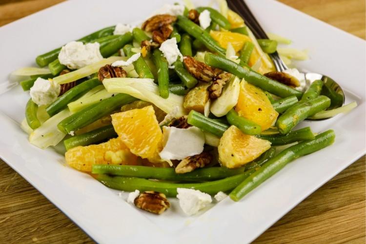A plate of fruit, pecan and green bean salad whit goat's cheese and fennel.