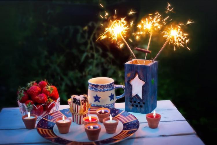 Fourth of July candles and sparklers with a bowl of fresh strawberies.