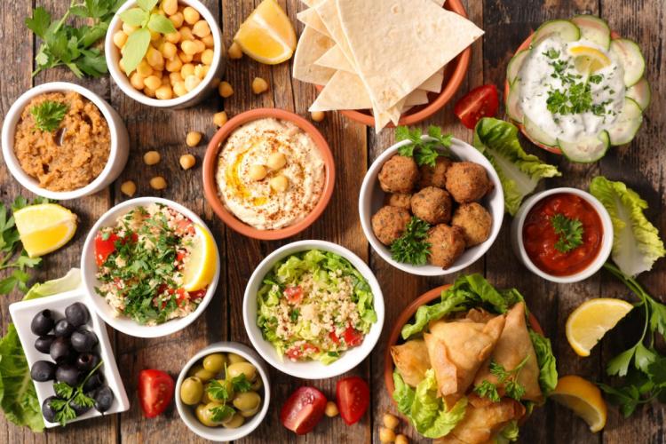 Top view of a Lebanese mezze platter featuring hummus, falafel, tabbouleh, baba ghanoush, olives, flatbread, and other traditional appetizers.