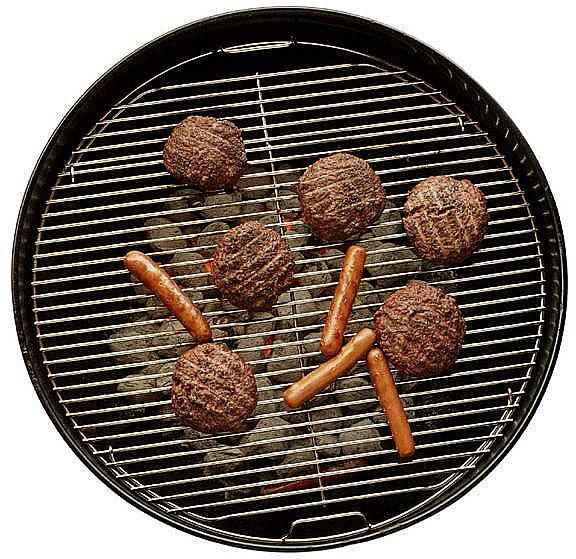Meat and sausages cooking on a charcoal barbecue.