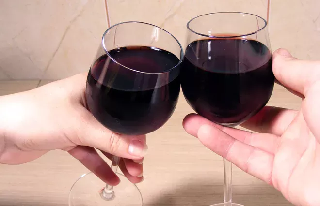 Hands holding red wine glasses and clicking.