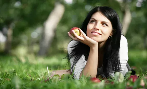 A young woman with an apple in the hand.