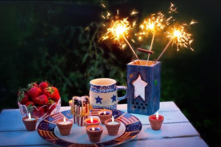 Fourth of July candles and sparklers with a bowl of fresh strawberies.