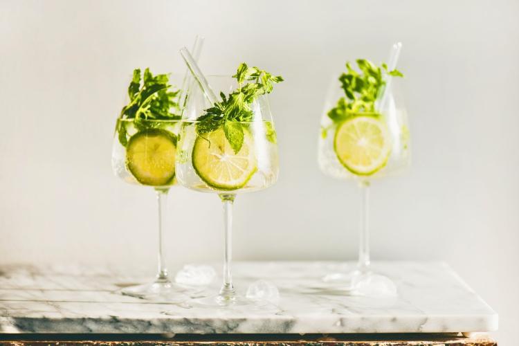 Three glasses of mint lime spritzes with lime slices and fresh mint on a marble surface.