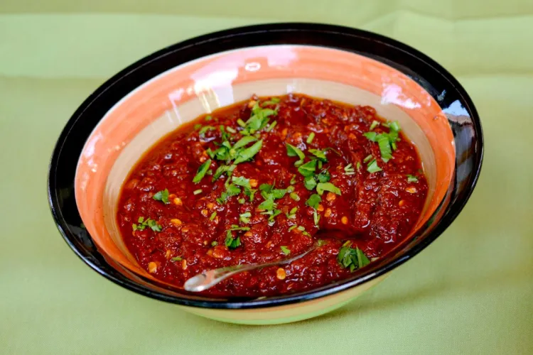 A bowl of redish pindjur dip garnished with fresh herbs.