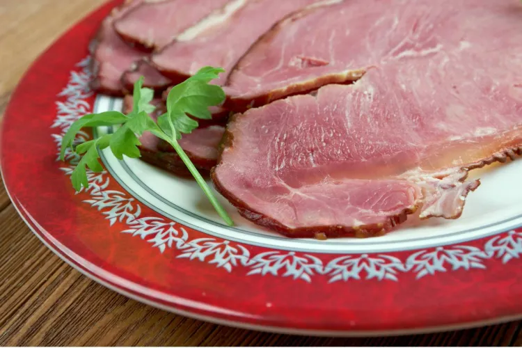 A plate of Icelandic hangikjöt, smoked lamb served with a white sauce and garnished with onions and red shavings