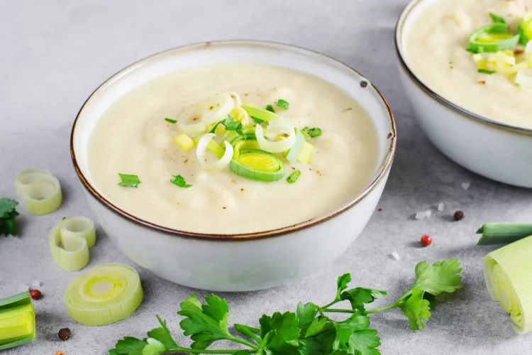 Creamy leek and potato soup garnished with fresh leeks and parsley.