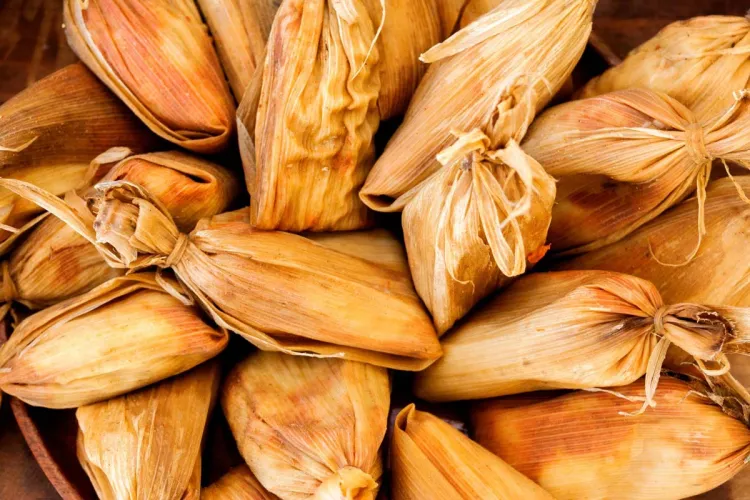 Guatemalan chuchitos wrapped in golden corn husks and piled together.