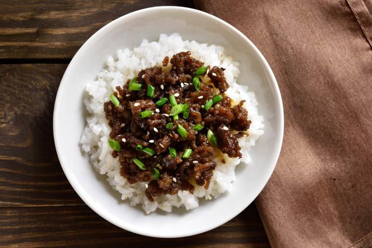 A bowl with white rice and ground beef in sauce.