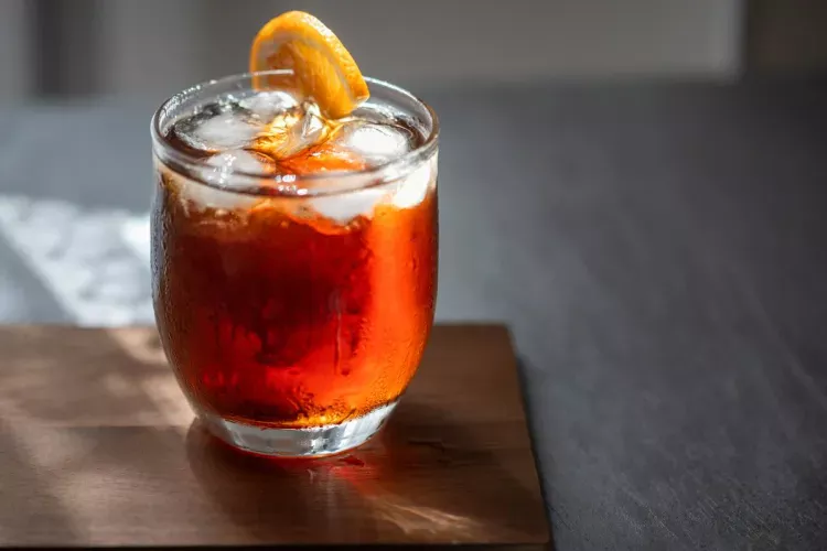 A glass of Vermouth with ice, decorated with a slice of orange.