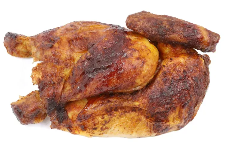 Whole spit-roasted chicken with deeply browned, crisp skin, spatchcocked and photographed from above on a plain white background