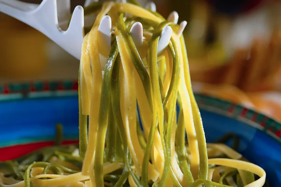 Pasta holder draining cooked tagliatelle our of the pan.