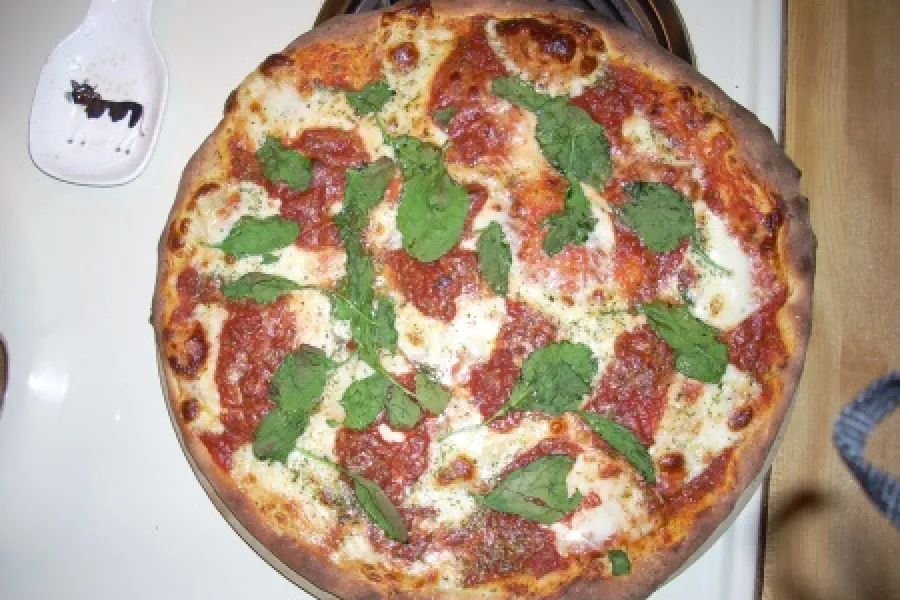 Pizza done with mozzarella and fresh basil.