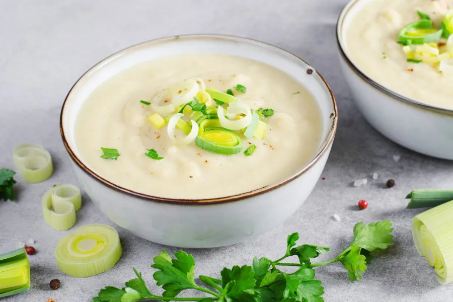 Creamy leek and potato soup garnished with fresh leeks and parsley.