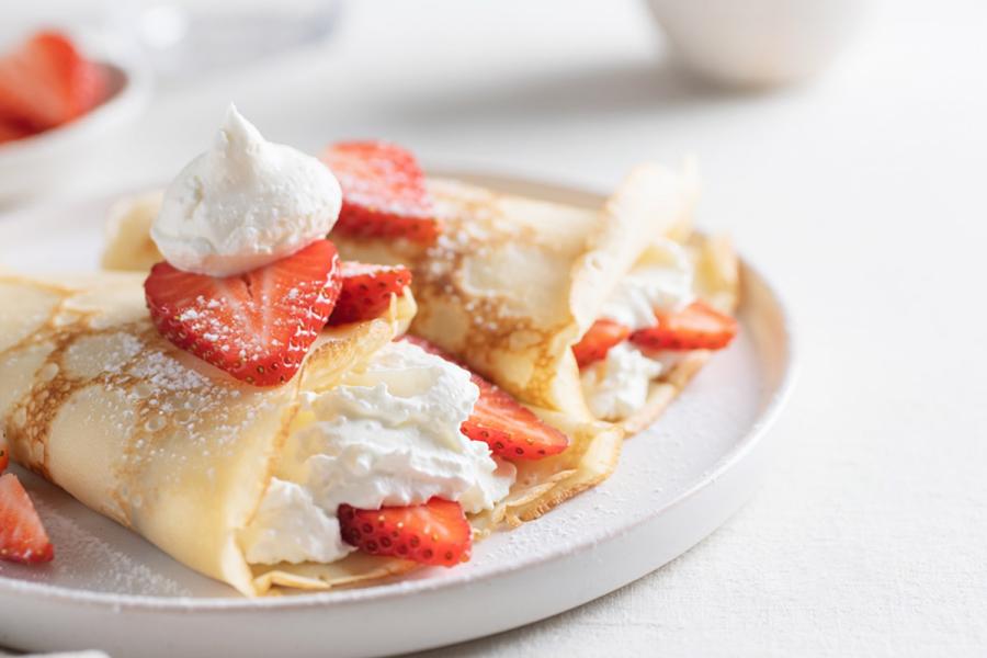 A plated serving of strawberries and cream crepes.